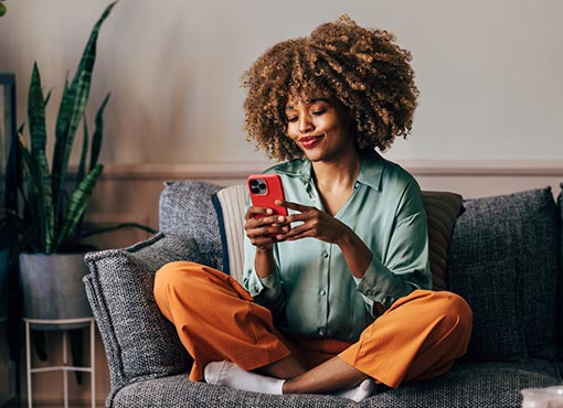 woman sitting on couch looking at mobile phone